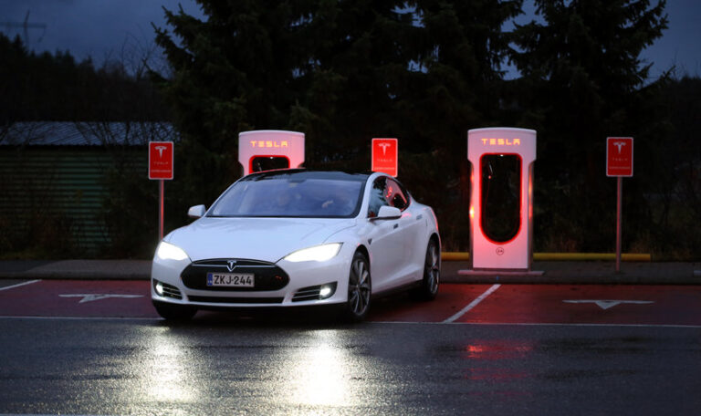 PAIMIO, FINLAND - NOVEMBER 14, 2015: Tesla Model S electric car arrives at the Paimio Tesla Supercharger station at night for charging. Tesla Supercharging stations are open any time.